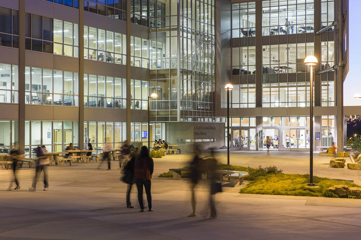 students standing and sitting in front of library